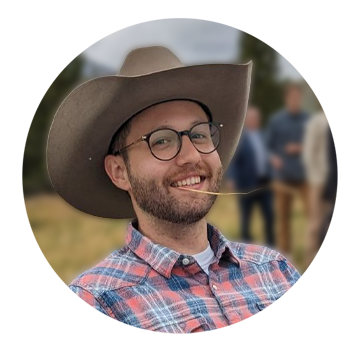 White man with glasses wearing a cowboy had and smiling