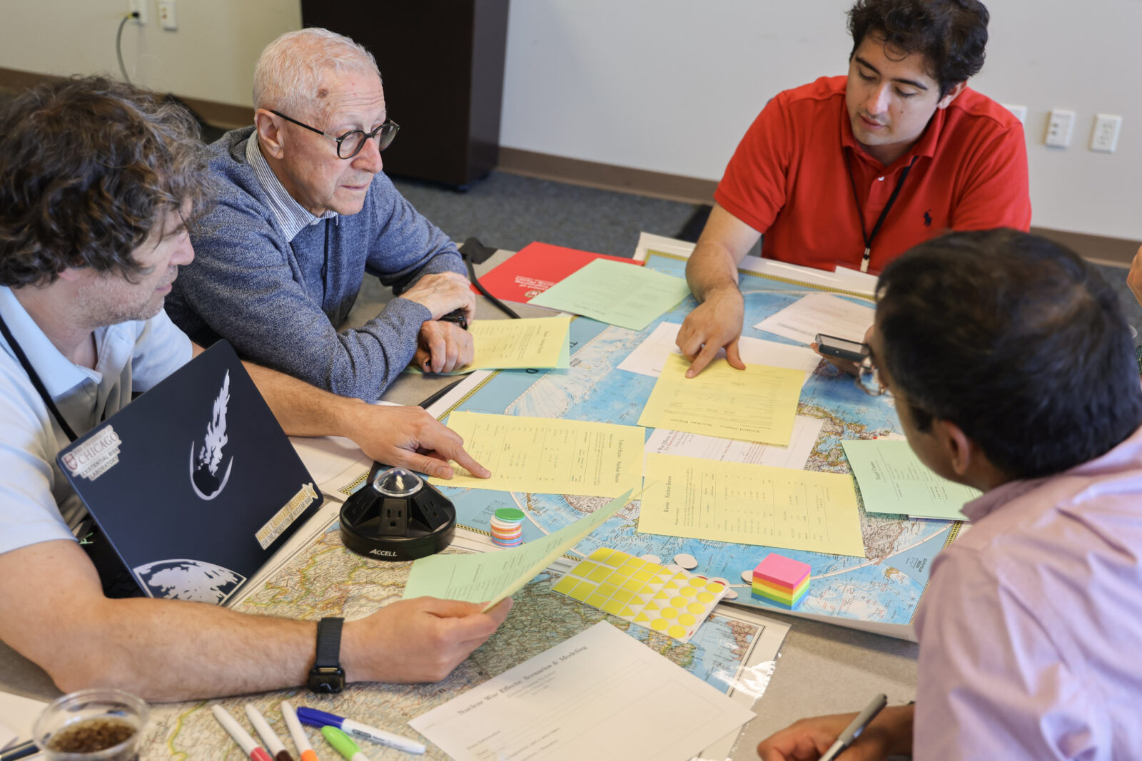 Participants at a nuclear war modeling workshop are discussing around a table.